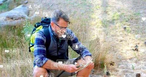 Hiker crouching on trail, tapping tablet with stylus checking route and causing Stock Photos