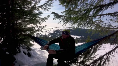 Hiker Drinking Cofee And Reading A Book, Lying In Hammock In Winter Forest Stock Footage 220736924