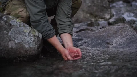 Hiker drinks water from a mountain stream. Stock Footage 166118591