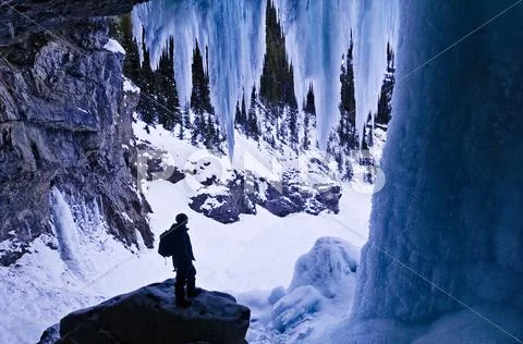 Hiker Dwarfed By Giant Icicles, Behind Panther Falls In Winter, Banff National