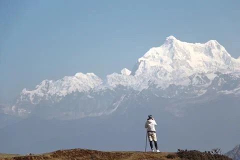 Hiker enjoys beautiful panoramic view of high mountains with snow Stock Photos