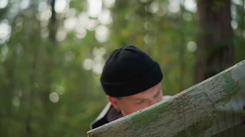 Hiker examines map, Person analyzes terrain details, Individual studies Stock Footage 329536117