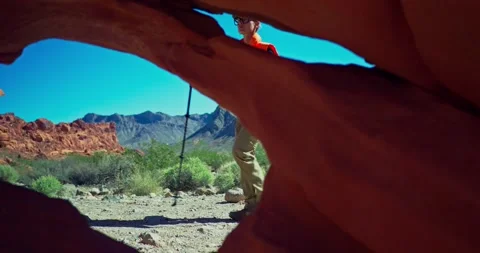 Hiker Exploring Desert Landscape Through Rock Archway 스톡 동영상 325448111