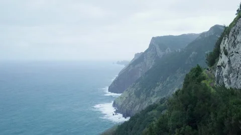 Hiker exploring a scenic coastal path in a dramatic mountain landscape Видео 333696015