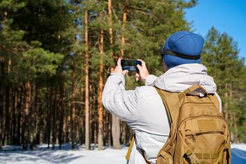 Hiker exploring a snow covered pine tree forest on a sunny winter day, usin.. Stock Photos