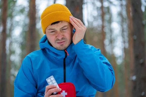 Hiker feeling strong headache touching head taking medicine from first aid kit Stock Photos