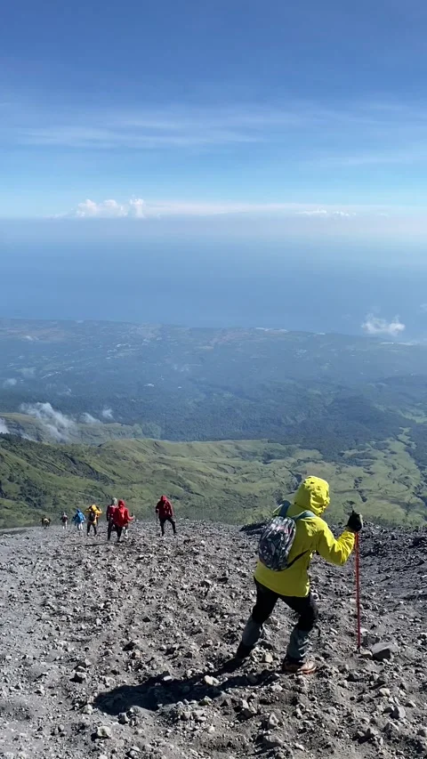 Hiker going down sandy slope hold a stick in clear day at Rinjani Mountain Trail Видео 332257254