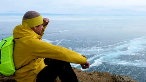 Hiker going to top and looking at ice of Baikal. Frozen lake Stock Footage 145630100