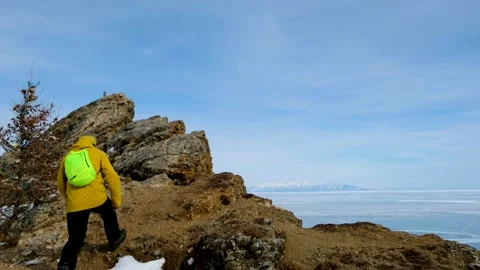 Hiker going to top and looking at ice of Baikal. Frozen lake Stock Footage 148076092