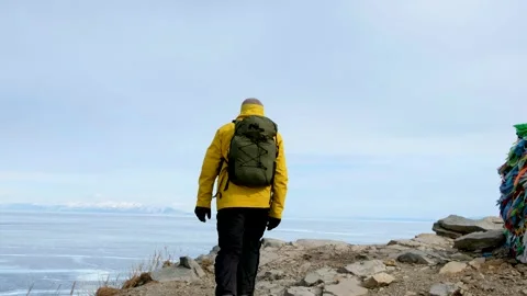 Hiker going to top and looking at ice of Baikal. Frozen lake Stock Footage 148076183
