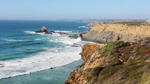 Hiker Greets Ocean from Cliff Edge on Portugals Coastal Trail Stock Footage 319318383