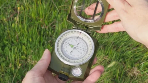 Hiker holds an open compass and uses it to navigate the outdoors during a s.. Stock Footage 339616583