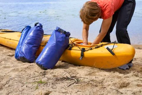 Hiker inserting a waterproof bag with the things into the kayak 写真素材