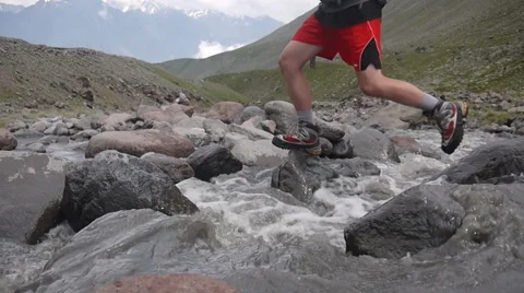 Hiker jumping over the river in mountains Stock-Footage 43249153