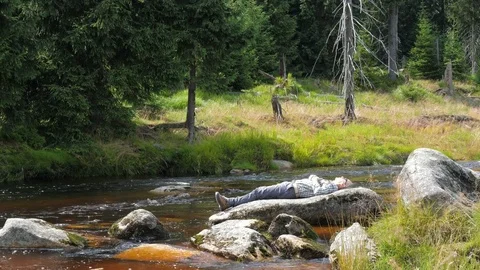 Hiker is lying on a boulder and is enjoying the nature. Rest in the nature Stock Footage
