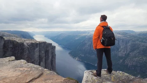 Hiker man with backpack standing on top of the mountain and admiring the scenery Stock Footage 87842584