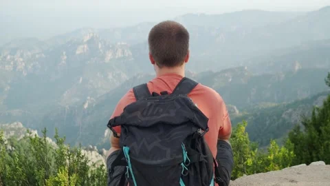 Hiker man from behind with a backpack sitting on top of the mountain. Stock Footage 157509605