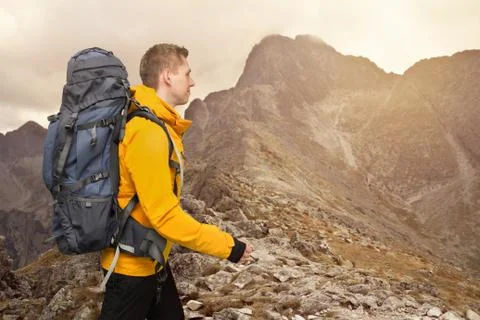 Hiker man with big backpack walking in sunset mountains Stock Photos