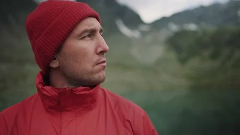 A hiker man in red jacket and hat is looking around among beautiful mountains Stock Footage 137941768