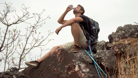 Hiker man take a break on the top mountain drinking water with walking pole . Stock Footage 162664531