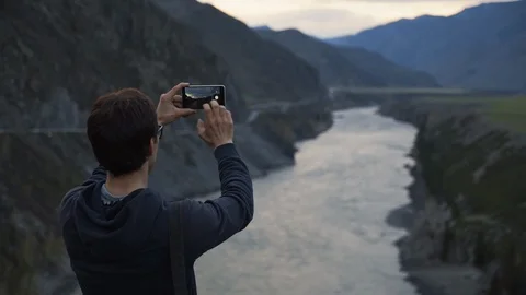 Hiker man Taking Cell Phone Picture of amazing view of wide mountain river. Stock Footage 103142646