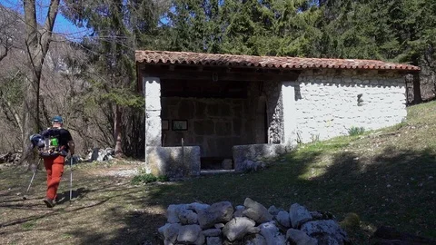 Hiker man walks on the forest path and passes near an old small church. Stock Footage 113269025