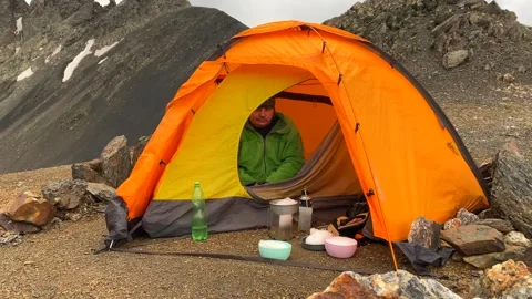 Hiker melting snow in close view beside an alpine tent in Svaneti Stock Footage 343770029