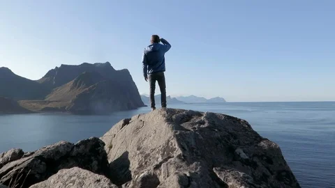 Hiker on mountain checking the ocean view, Unstad, Lofoten Stock Footage 90081643