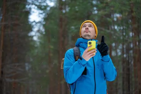 Hiker navigating forest path using smartphone, man looking up, lost in Stock Photos