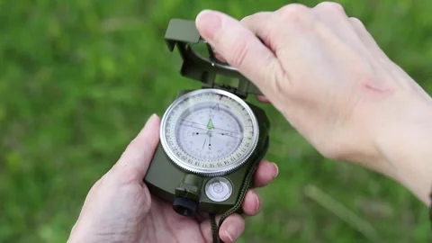 Hiker opens a compass and uses it to navigate during a summer hike. Stock Footage 340285014
