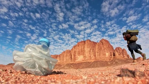 Hiker passing discarded plastic bottle in Wadi rum desert pollution awarene.. Stock-Footage 330260212