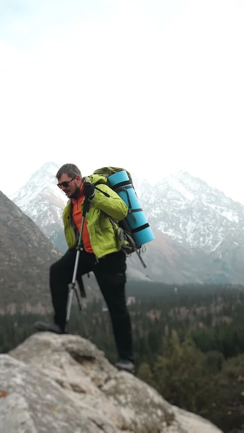 Hiker Reaching Mountain Peak and Looking Around Vertical Outdoor Adventure. Vídeo Stock 321576559