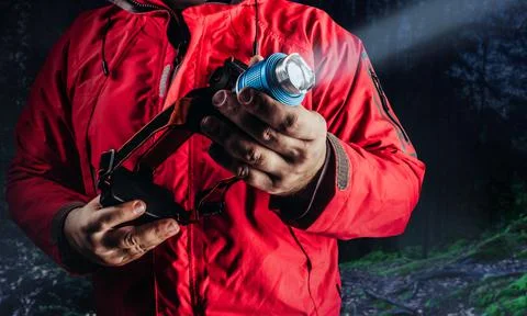 Hiker in red jacket holding flashlight. Stock Photos