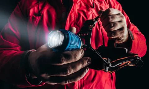 Hiker in red jacket holding flashlight. Stock Photos