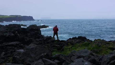 Hiker in Red Jacket Standing on Rocky Coastline Iceland Stock Footage 341295162