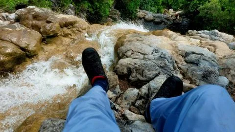 Hiker Resting By Cascading Waterfall Stream In Lush Mountain Nature Stock Photos