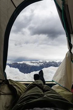 Hiker Resting Inside a high altitude camping Tent with pristine Snowy Mount.. Fotos Stock