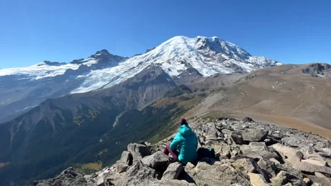 Hiker resting on rocks while viewing Mount Rainier. Stock Footage 241797162