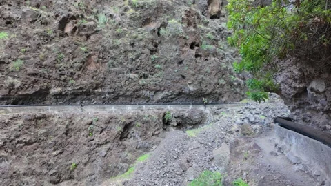 Hiker on a rugged mountain path on Tenerife along water pipes Stock Footage 340230385