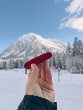 Hiker showing multitool while hiking in snowy mountain landscape 库存照片