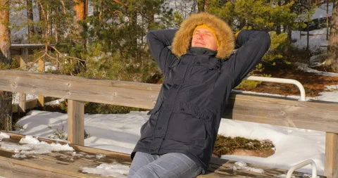 Hiker sitting on the bench in the sun in winter Nuuksio national park, Finland Stock Footage 122122053
