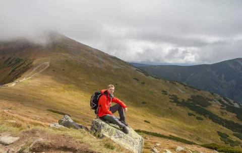 Hiker sitting on rock builder in mountains Stock Photos