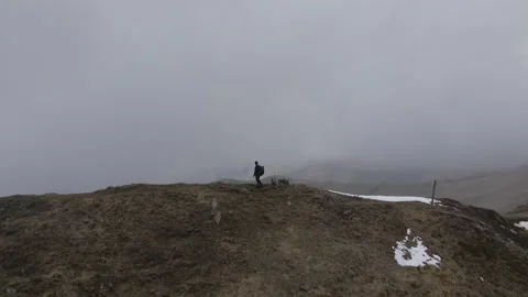 Hiker standing on the top of the mountain watching the panorama while snowing Stock Footage 215917994