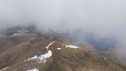 Hiker standing on the top of the mountain while snowing Stock Footage 215914517