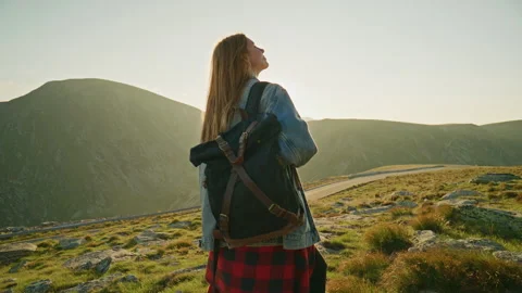 Hiker stands on mountain path during sunset with backpack in scenic landscape Stock Footage 345631452