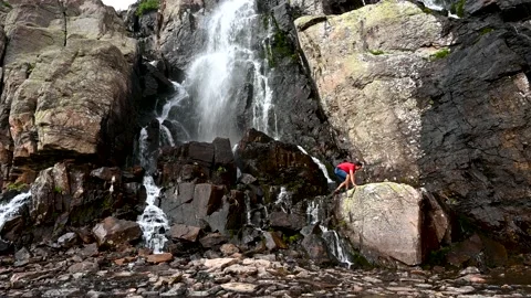 Hiker stands next to waterfall Stock Footage 159028733
