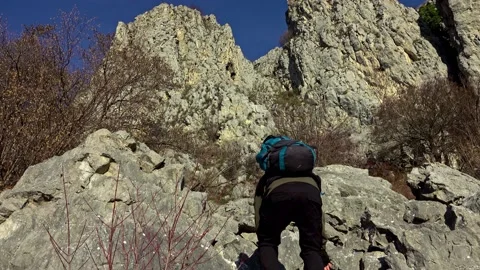 Hiker on the steep scree terrain to the summit of the mountain Видео 224063498