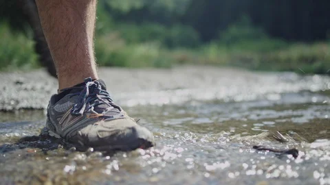 Hiker steps in stream as he walks in mountains Stock Footage 127461049