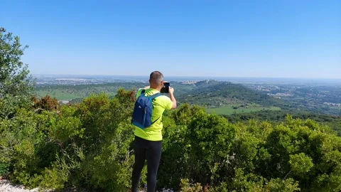 Hiker taking pictures at the Top of a Mountain 4K on a Sunny Day with Blue Sky Stock Footage