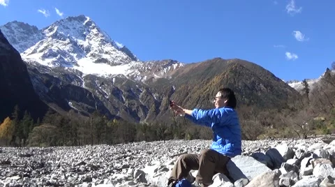 Hiker taking self portrait with a cell phone in the snow mountain area Stock Footage 43505192